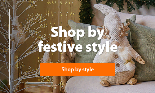 A heading 'Shop by festive style' accompanied by a room with beautiful Christmas decor and a Christmas tree with modern decorations and warm white lights