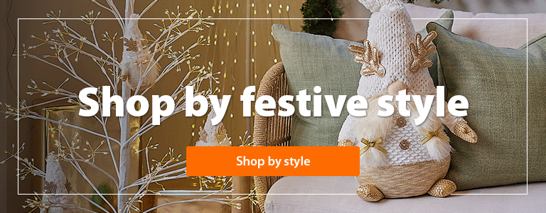 A heading 'Shop by festive style' accompanied by a room with beautiful Christmas decor and a Christmas tree with modern decorations and warm white lights