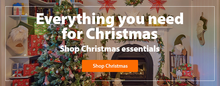 A heading 'Everything you need for Christmas, shop Christmas essentials' accompanied by an outdoor area with an outdoor table, Christmas tree & decor, BBQ and presents under the tree